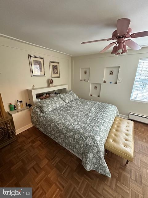 bedroom featuring dark parquet floors, ceiling fan, and baseboard heating