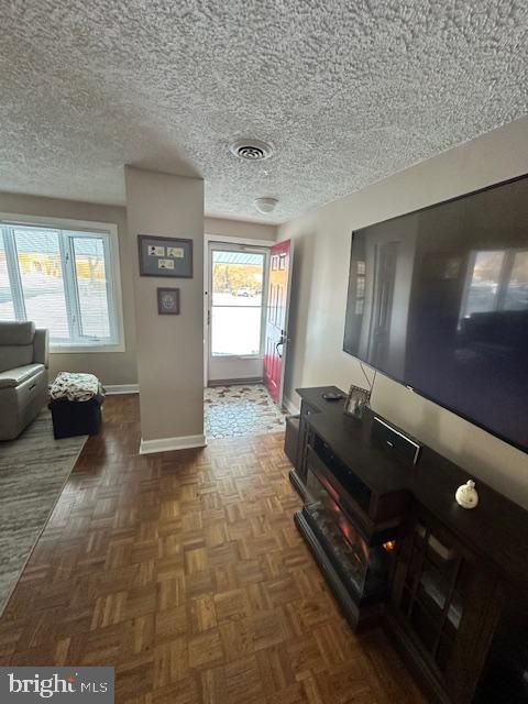 living room with dark parquet flooring and a textured ceiling