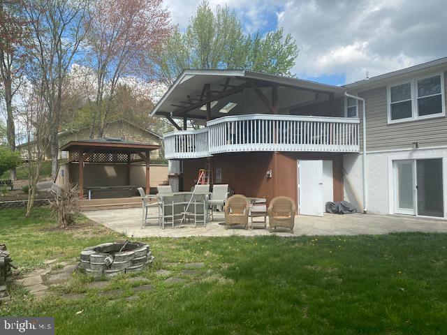 rear view of property featuring a gazebo, a lawn, a patio area, and an outdoor fire pit