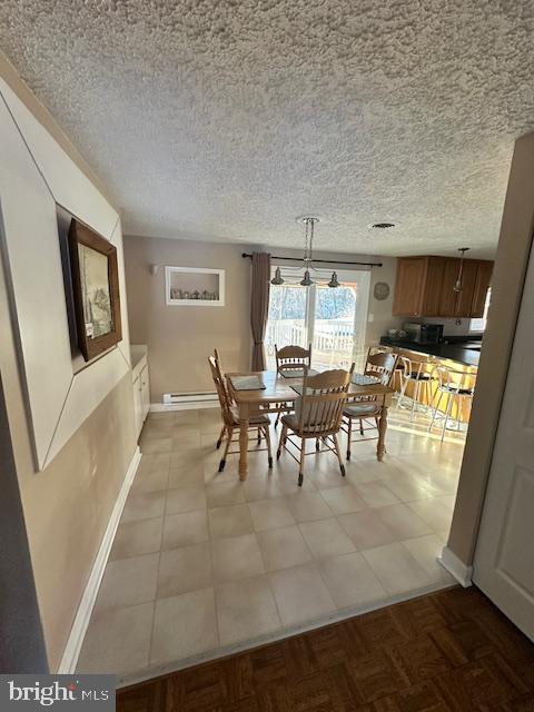 dining room featuring light parquet floors, a baseboard heating unit, and a textured ceiling