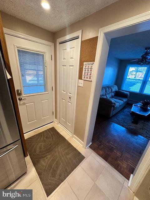 tiled foyer featuring ceiling fan and a textured ceiling