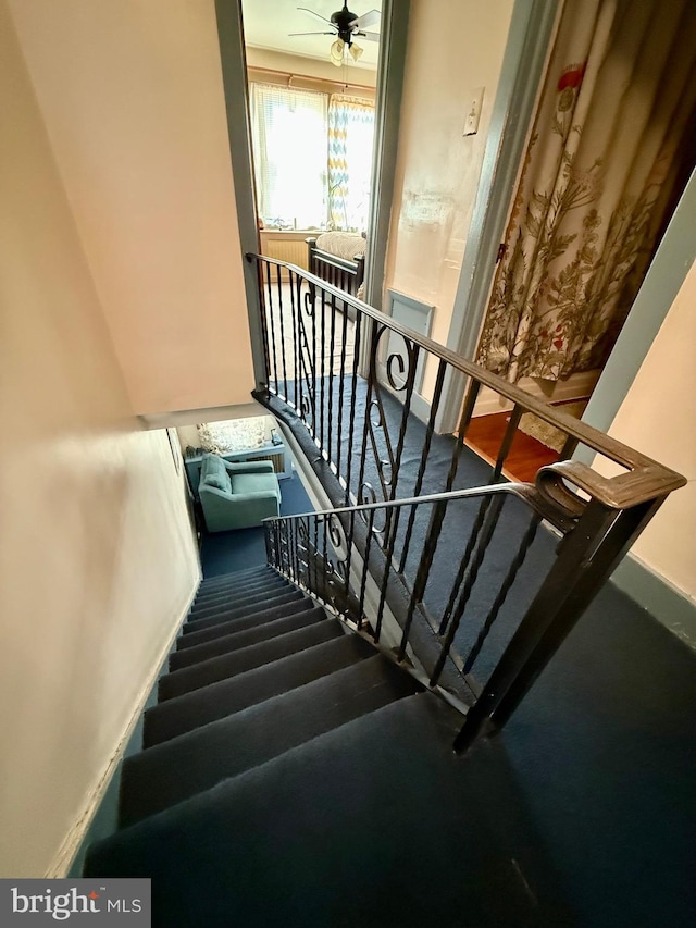 stairway featuring ceiling fan