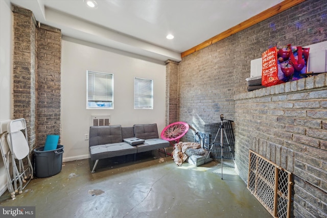 interior space with a brick fireplace, concrete flooring, and brick wall