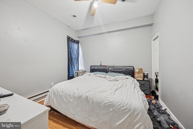 bedroom with a baseboard heating unit, hardwood / wood-style floors, and ceiling fan