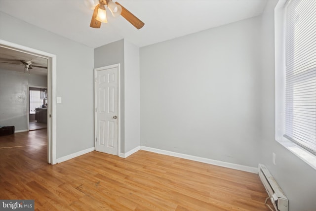 interior space with baseboard heating, ceiling fan, and wood-type flooring