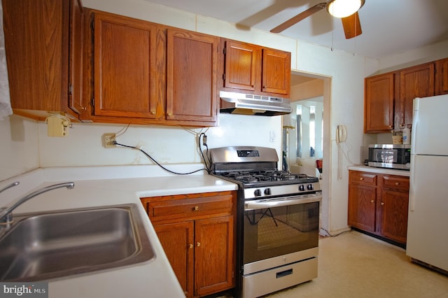 kitchen featuring brown cabinetry, stainless steel appliances, light countertops, under cabinet range hood, and a sink