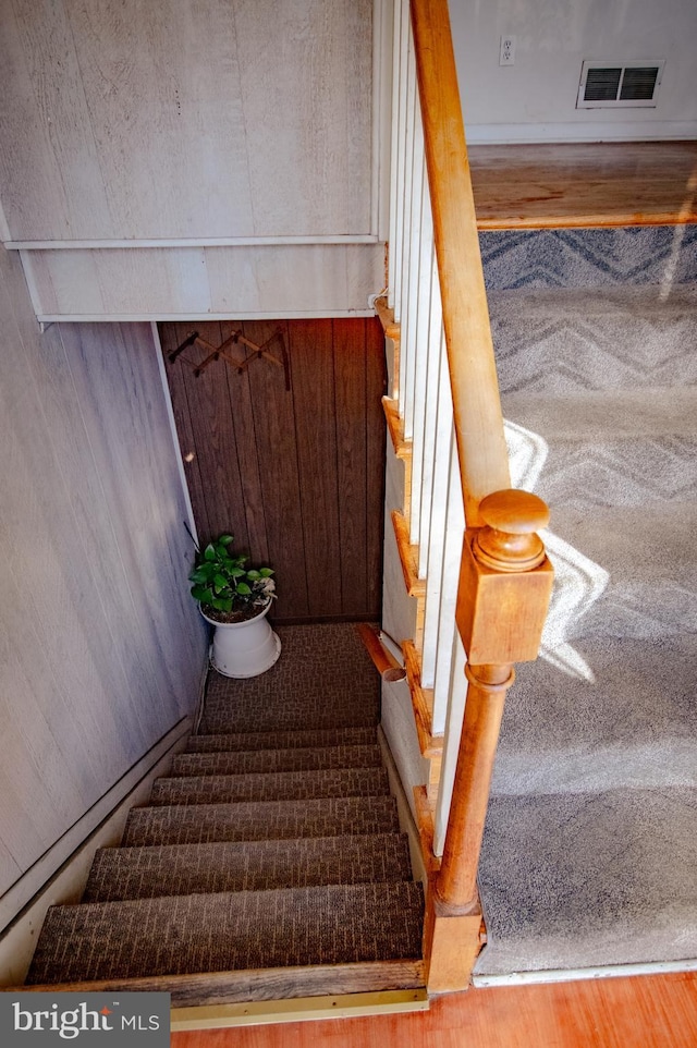 stairway featuring visible vents and wood finished floors