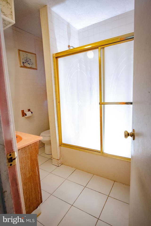 bathroom featuring tile patterned flooring, toilet, tile walls, and vanity