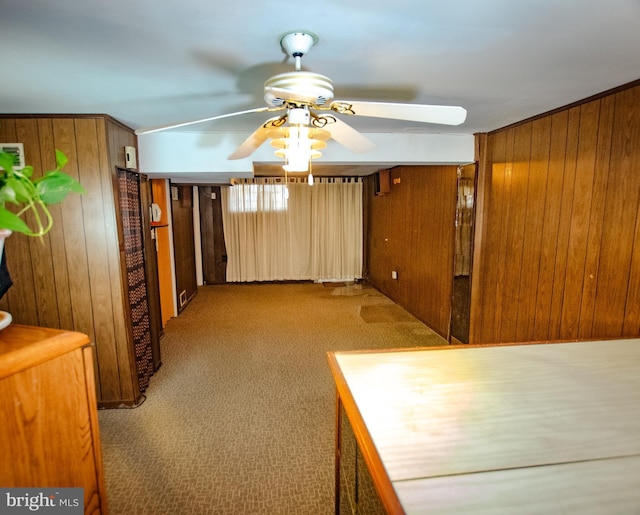 interior space featuring wood walls, carpet, and a ceiling fan