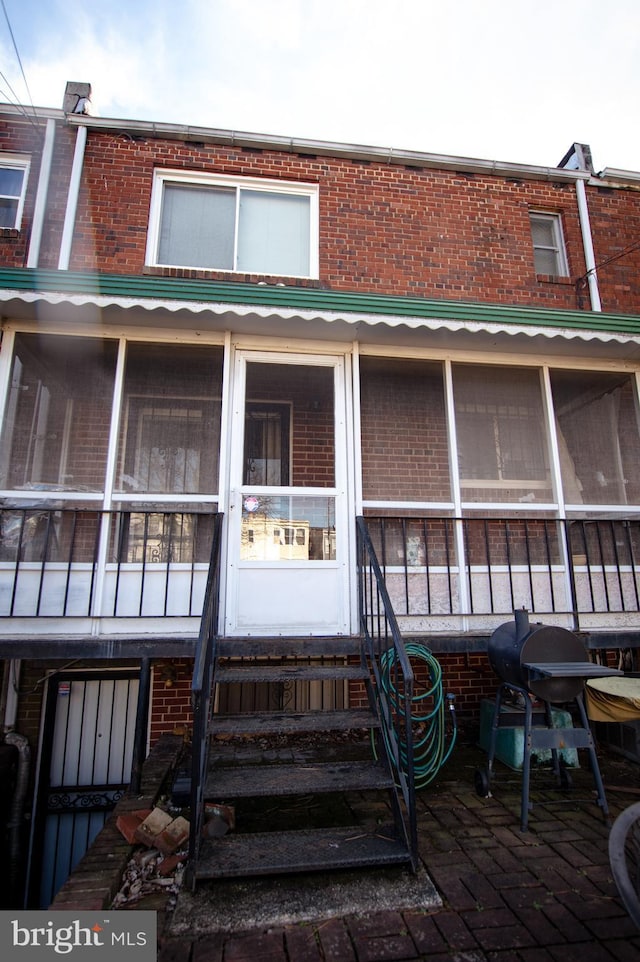 back of house featuring entry steps, brick siding, and a sunroom