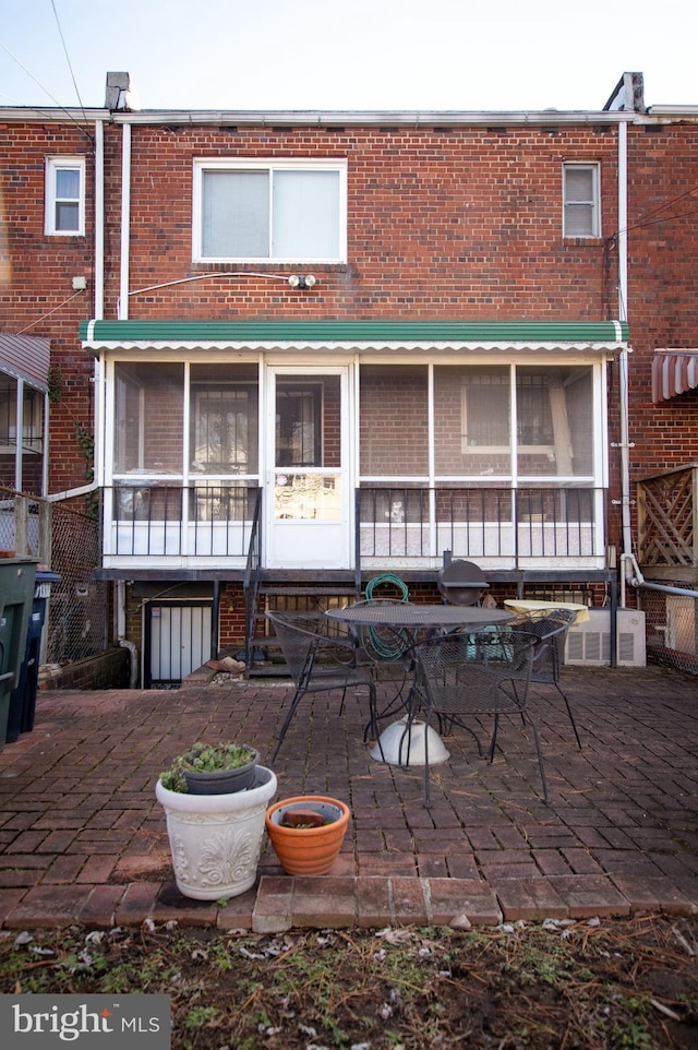 back of house featuring entry steps, a patio area, and brick siding