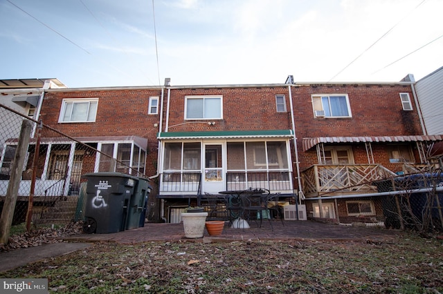 rear view of property featuring a sunroom and brick siding