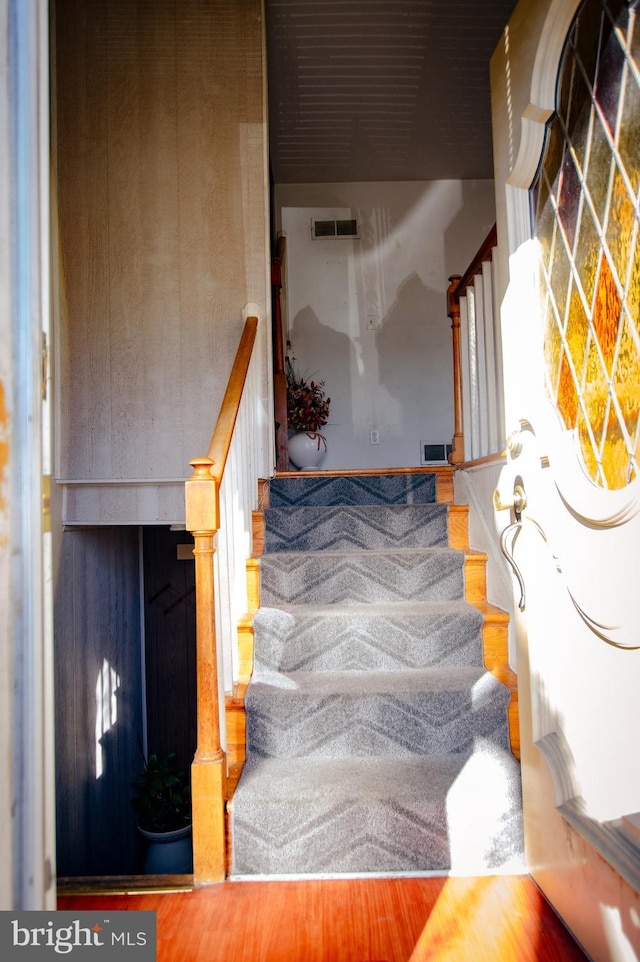 stairway with visible vents and wood finished floors