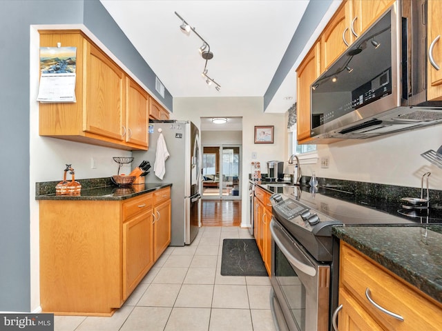 kitchen featuring light tile patterned floors, sink, stainless steel appliances, and dark stone counters