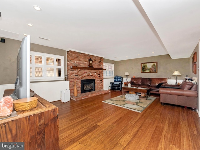 living room with hardwood / wood-style flooring and a brick fireplace