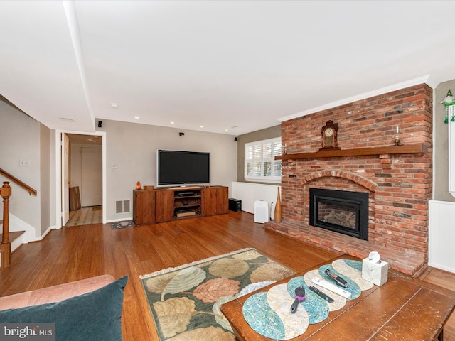 living room with hardwood / wood-style flooring and a brick fireplace