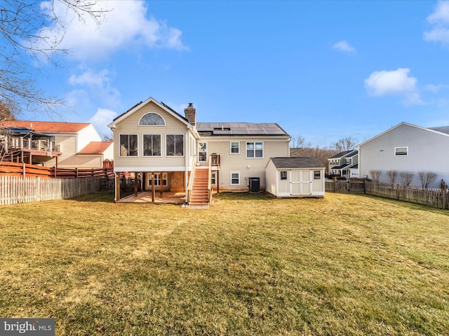 back of property featuring cooling unit, a yard, a patio area, solar panels, and a storage unit