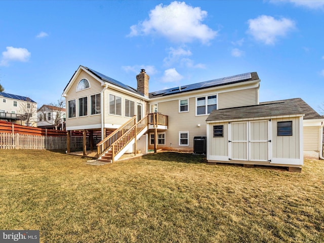 rear view of property featuring a storage shed, a deck, a yard, central AC unit, and solar panels