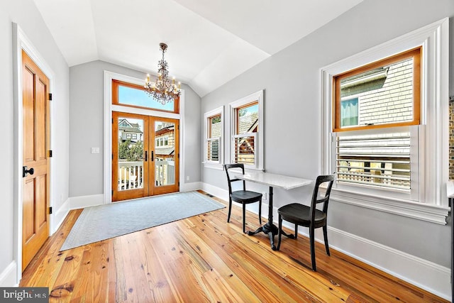 foyer entrance featuring lofted ceiling, an inviting chandelier, light hardwood / wood-style floors, and french doors