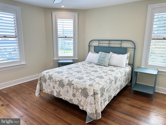 bedroom featuring multiple windows and dark hardwood / wood-style flooring