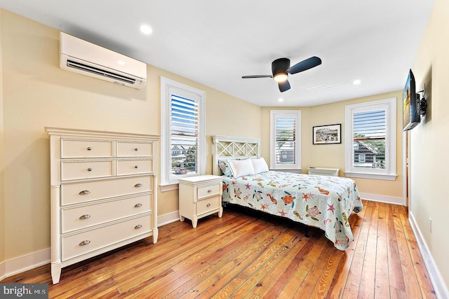 bedroom featuring ceiling fan, light hardwood / wood-style floors, and an AC wall unit