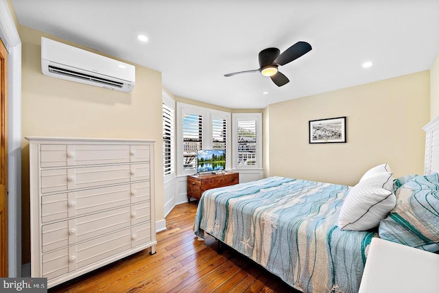 bedroom with ceiling fan, dark hardwood / wood-style floors, and a wall mounted AC