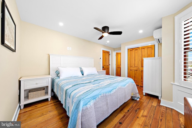 bedroom with wood-type flooring, a wall unit AC, a closet, and ceiling fan