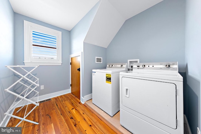 laundry area with separate washer and dryer and light wood-type flooring