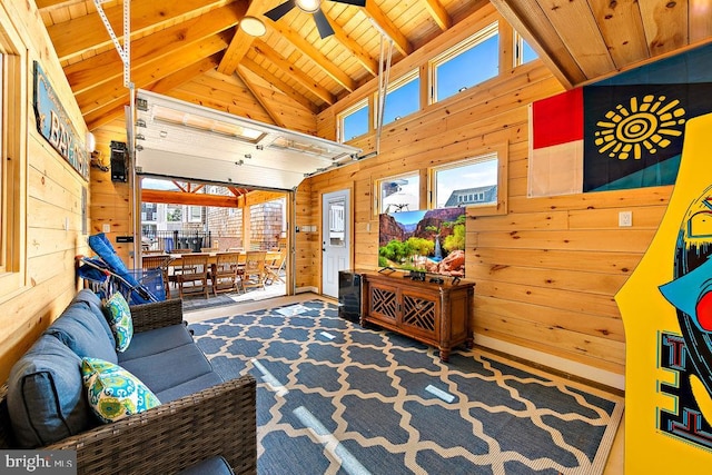 living room with beam ceiling, ceiling fan, wood ceiling, and wooden walls