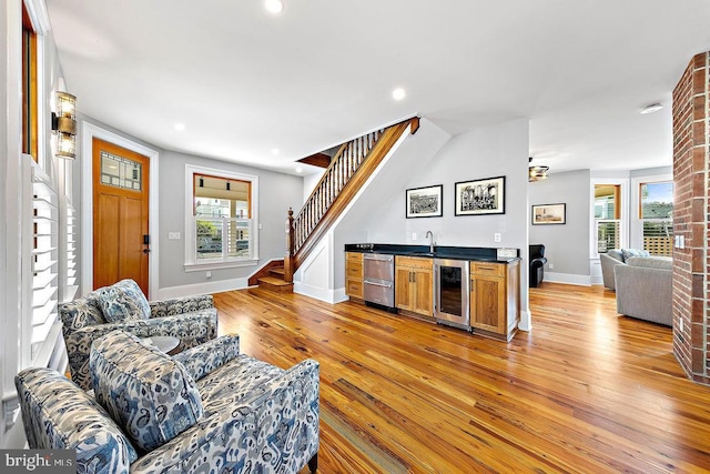 living room featuring beverage cooler, light hardwood / wood-style floors, and wet bar