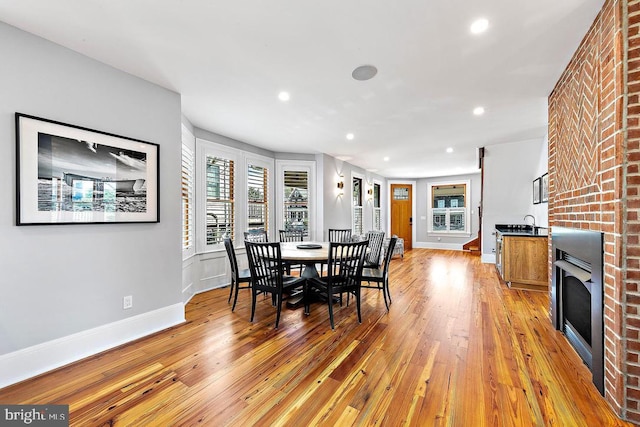 dining room with light hardwood / wood-style floors and a large fireplace