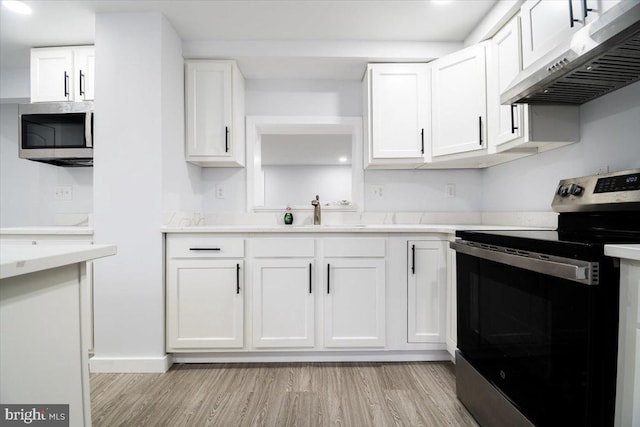 kitchen featuring stainless steel appliances, white cabinetry, sink, and light wood-type flooring