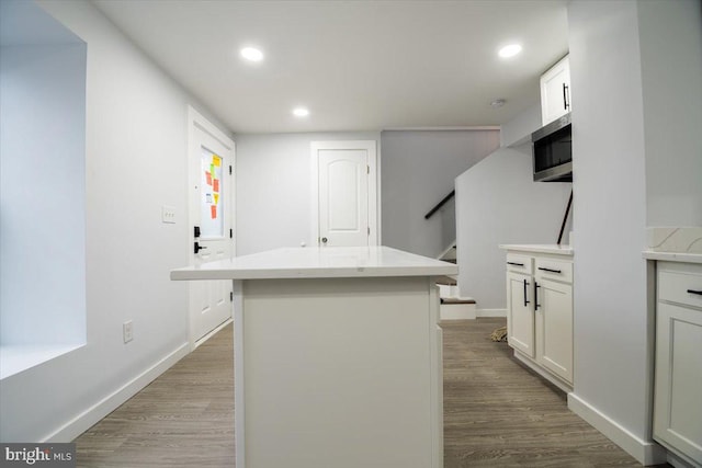 kitchen with white cabinetry, a center island, and light hardwood / wood-style flooring