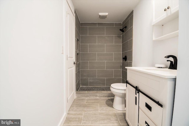 bathroom featuring vanity, tiled shower, and toilet