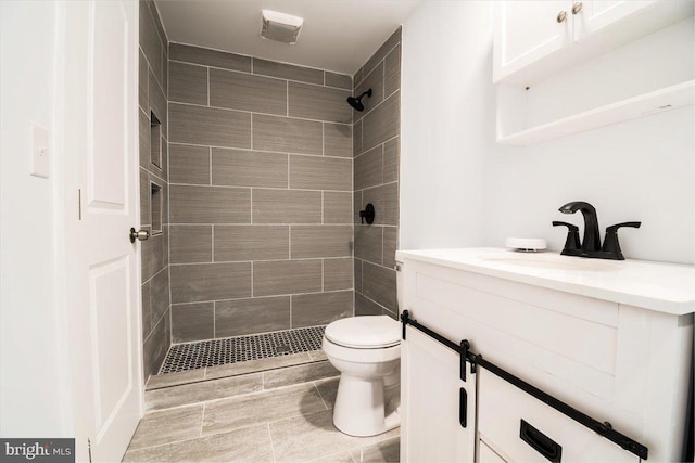 bathroom featuring vanity, toilet, and tiled shower