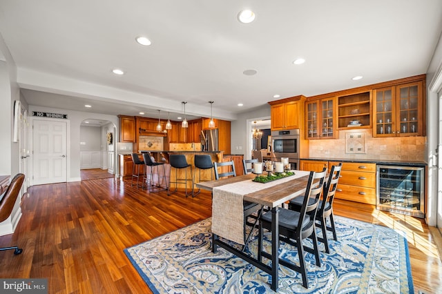 dining room featuring wine cooler, arched walkways, dark wood finished floors, and recessed lighting