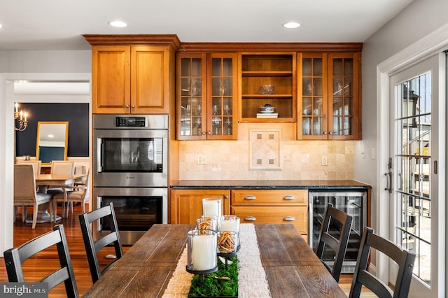 kitchen featuring a wealth of natural light, double oven, brown cabinetry, glass insert cabinets, and wood finished floors