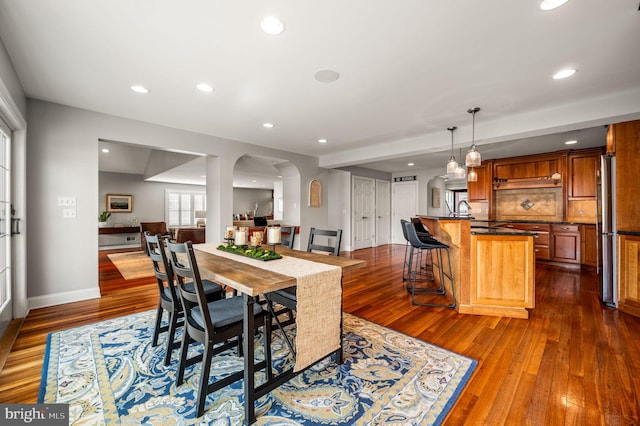 dining area with dark wood-style floors, baseboards, arched walkways, and recessed lighting