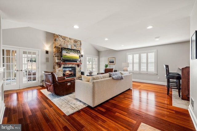 living room featuring lofted ceiling, a fireplace, wood finished floors, and french doors