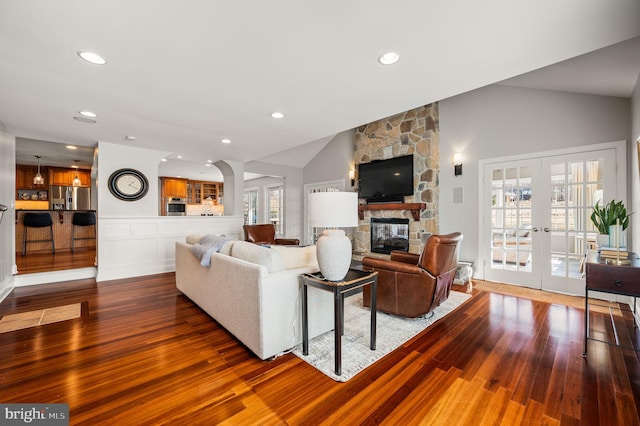 living room featuring lofted ceiling, french doors, a fireplace, and wood finished floors