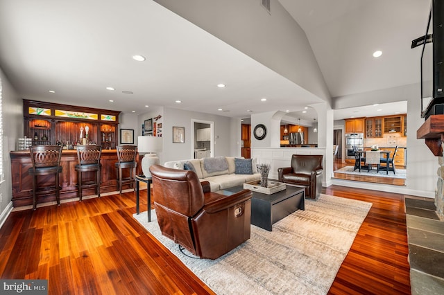 living room featuring recessed lighting, wood finished floors, visible vents, bar area, and vaulted ceiling