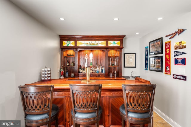 bar featuring wet bar, baseboards, and recessed lighting