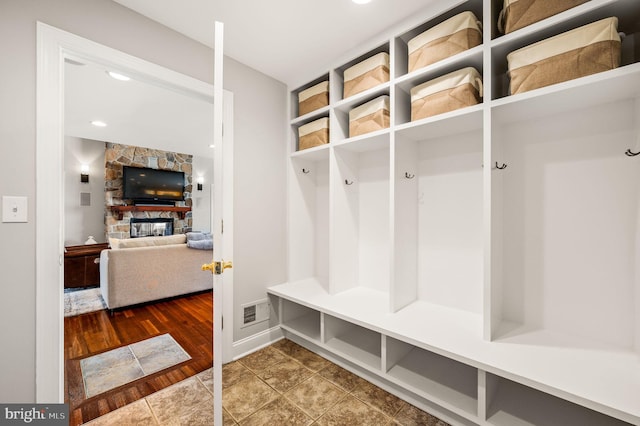 mudroom featuring dark wood-style floors, a fireplace, and visible vents