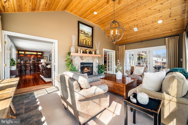 living area with french doors, a chandelier, wood ceiling, a stone fireplace, and high vaulted ceiling