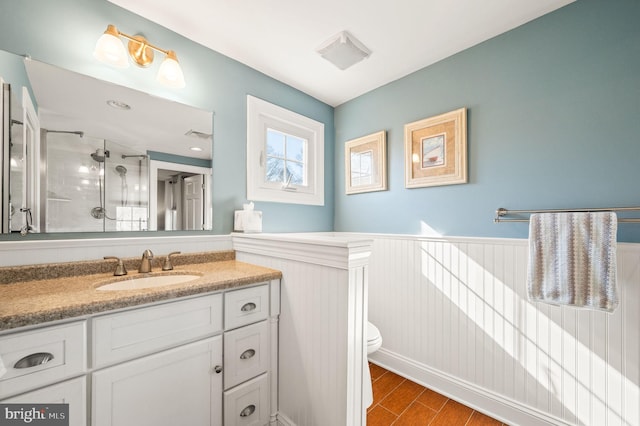 full bath featuring toilet, a wainscoted wall, wood finished floors, vanity, and visible vents