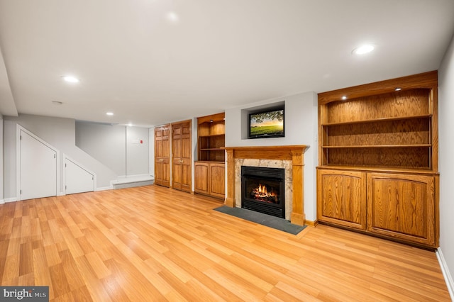 unfurnished living room featuring light wood finished floors, a fireplace, built in shelves, and recessed lighting