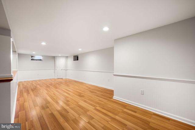 finished below grade area with recessed lighting, a wainscoted wall, and light wood-style flooring