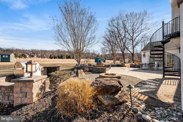 view of yard featuring stairs, a fire pit, area for grilling, and a patio