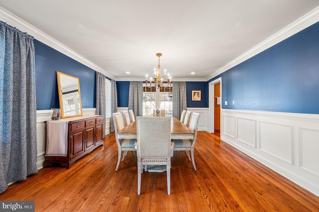 dining room featuring dark wood-style flooring, a wainscoted wall, crown molding, and an inviting chandelier