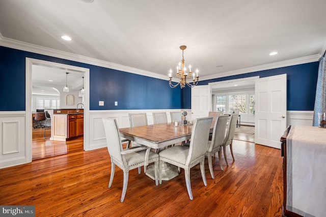 dining space with a wainscoted wall, light wood-type flooring, and a wealth of natural light